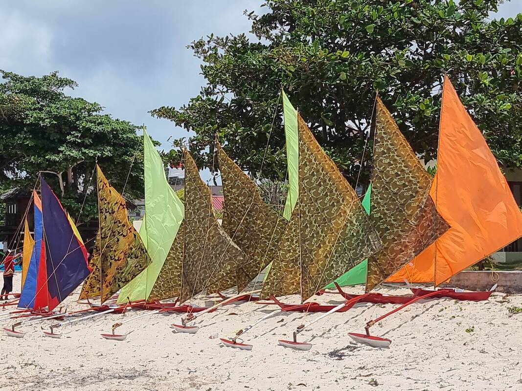 Jongs laid out on the sand in rows for judging, dozens of colors