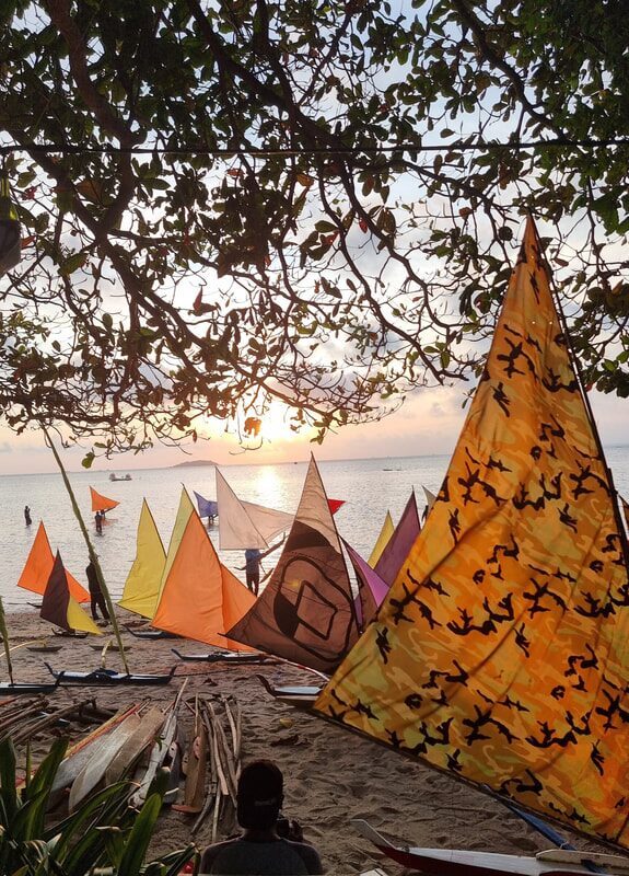 A golden sail glowing against the trees at dusk