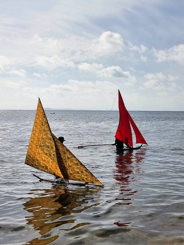 A single jong sailing on the water, red sail catching the wind