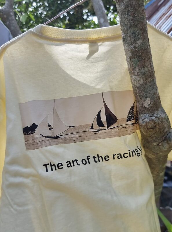 Close-up of a Jong School t-shirt hanging outdoors, printed with a sepia photo of racing jongs and 'The art of the racing jong'