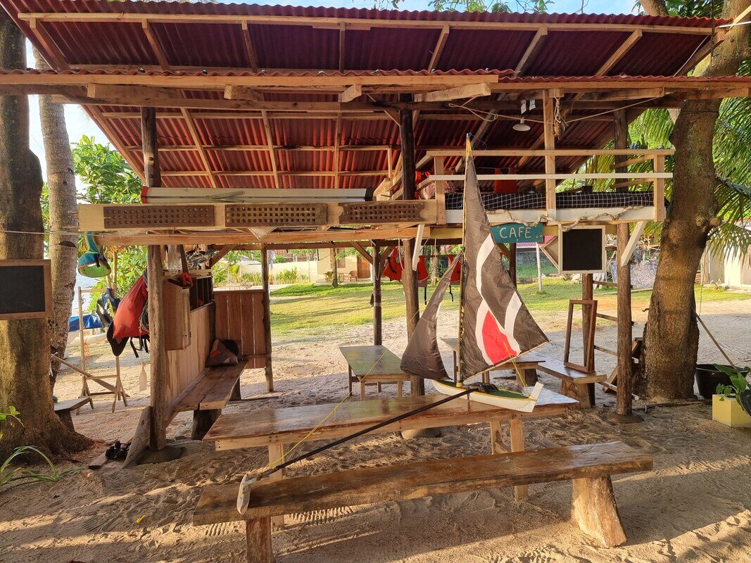 A jong with a striped black, white and red sail hanging under the covered deck of Planet Samudra cafe
