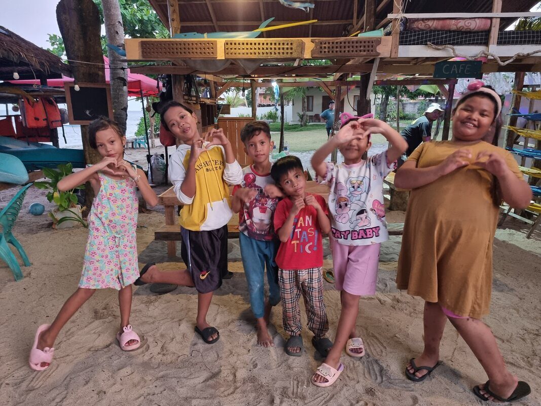 A group of kids and adults gathered around a jong on the sand