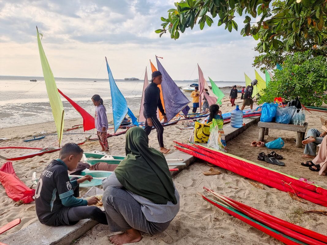 A jong pulled up on the beach beside two men working