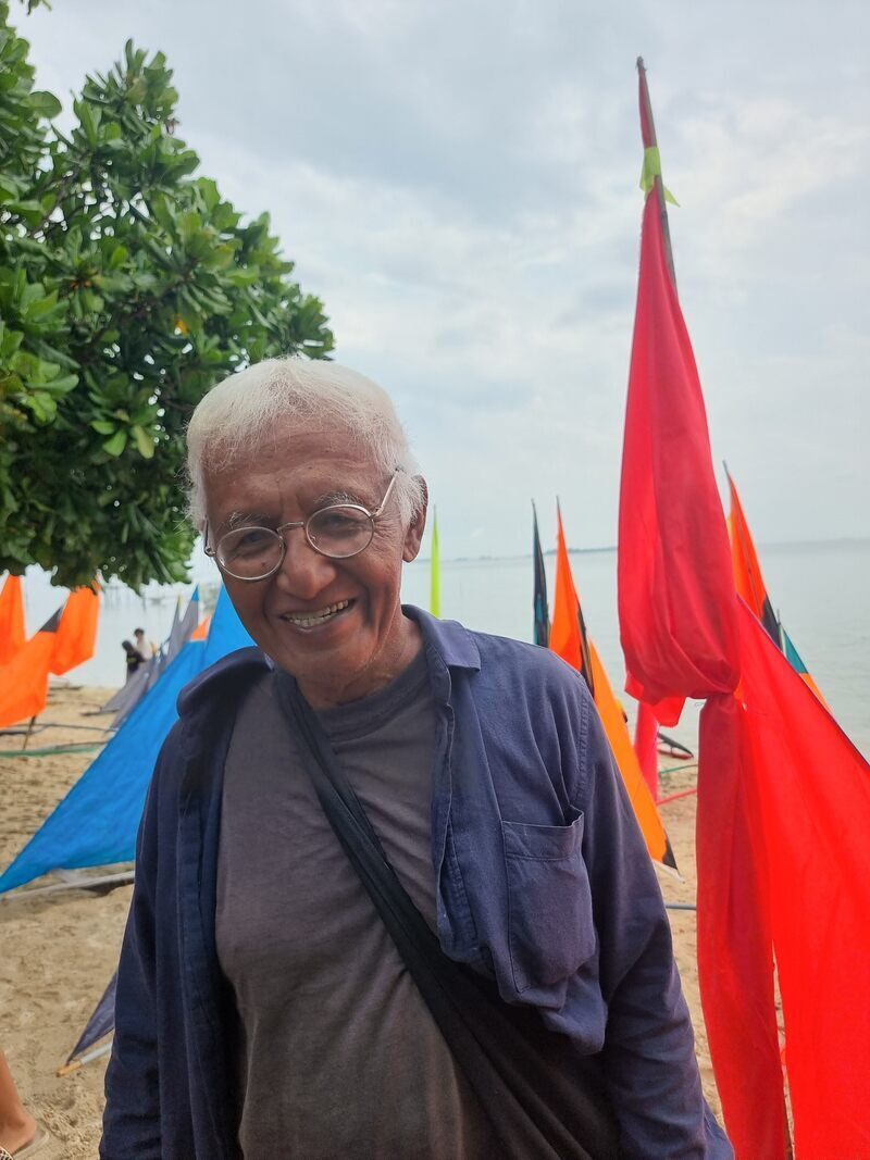 Portrait of an older man standing among red and yellow jong sails