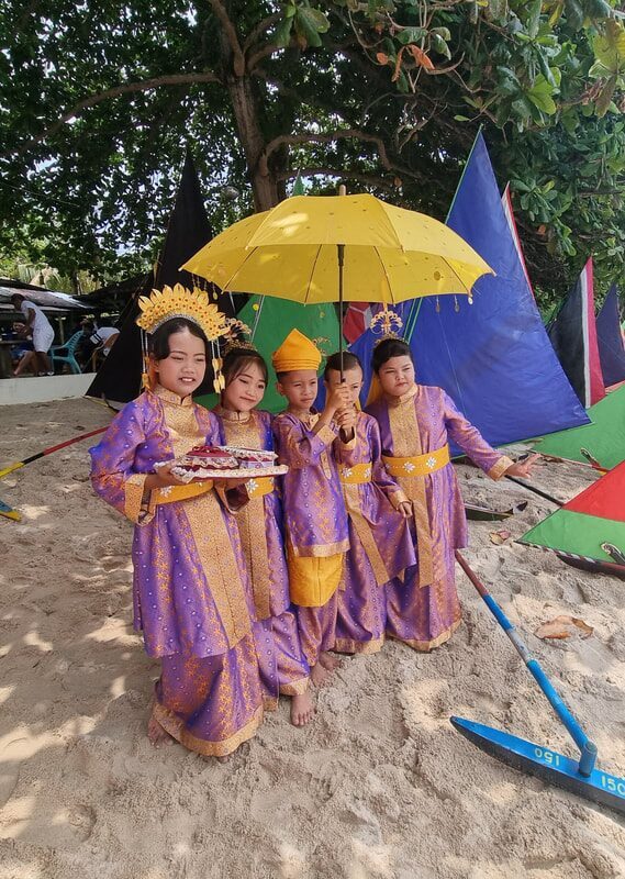 A girl in purple traditional dress under a yellow umbrella, sails behind her