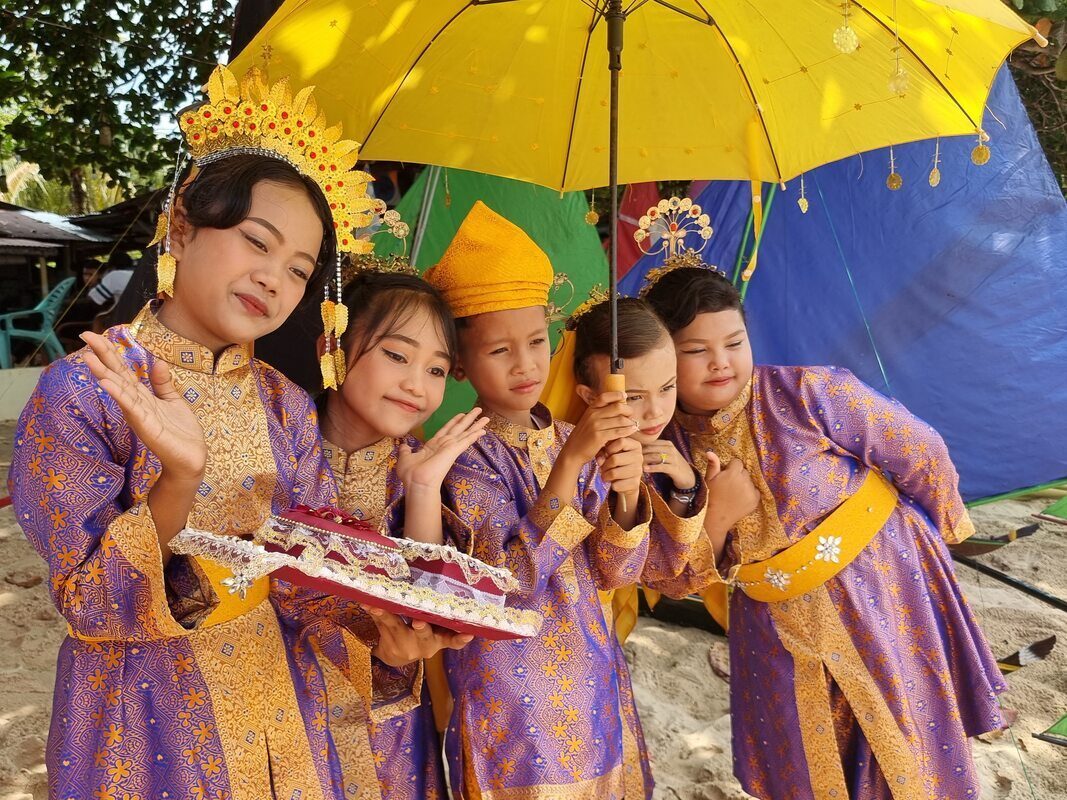 A group of girls in matching purple and gold traditional dress, one eating