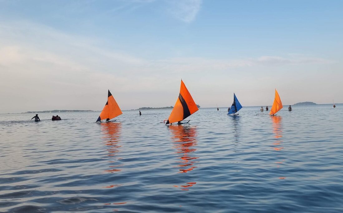 A jong sailing solo, seen from a distance across the water