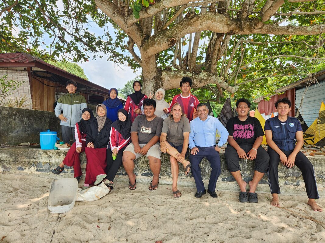 A group photo on the beach, several people posing together