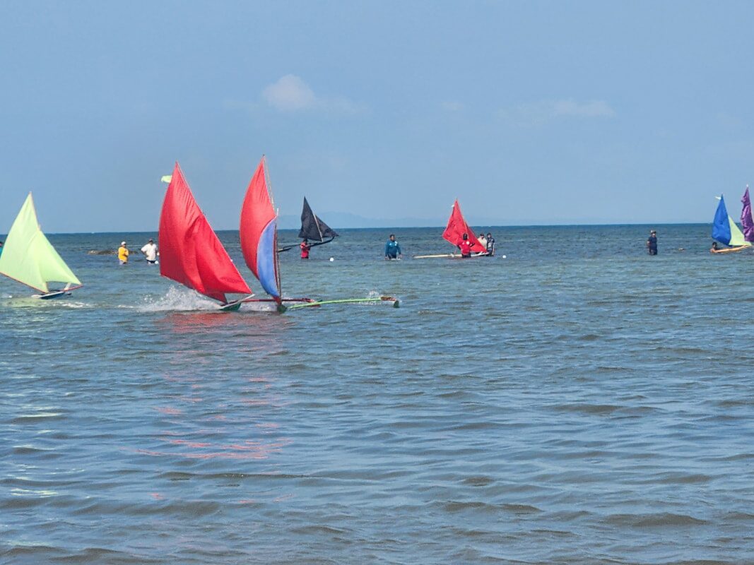 A row of jongs pulled up on the beach, colorful sails catching the light