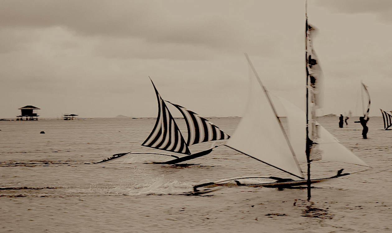 Sepia-toned photo of jongs racing in the shallows, striped and plain white sails, a stilt hut on the horizon