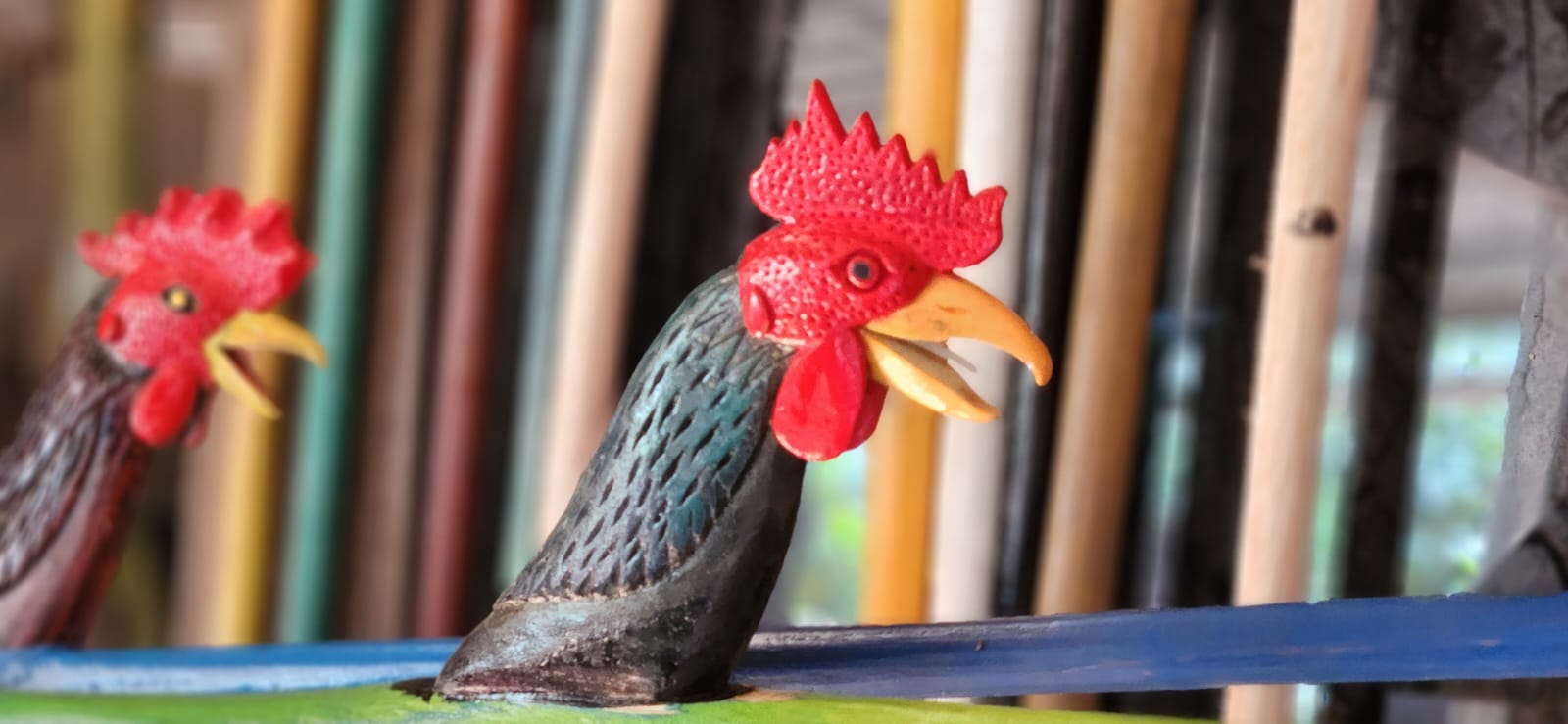 Close-up of two hand-carved wooden rooster figureheads mounted on jong hulls